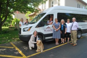 Behind the wheel of the new shuttle bus at the WCA Home is Activity Director Barb Jones. Also in the photo are, left to right in back: Board Members Lucinda Coon and Mary Sue Vogel; Board President Christine Davis Mantai (with the home’s pet, Smidgy);  Administrator Tammy McCool, Program Director Eileen Dunn of the Northern Chautauqua Community Foundation, and Board Members Karen Davis and Richard Halas.